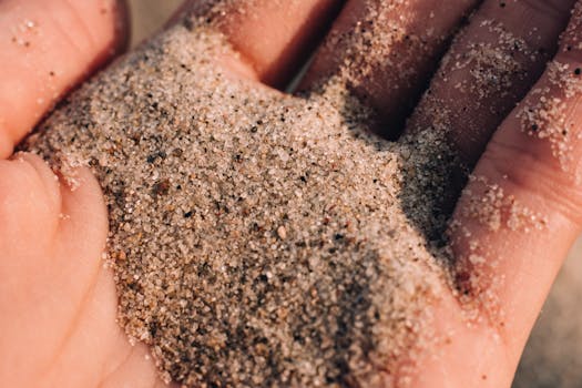 Detailed close-up of sand slipping through fingers on a warm sunny day.