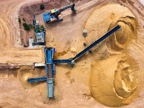 Top view of sand mining machinery and piles in outdoor quarry.